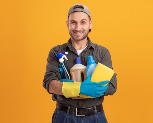 happy-young-cleaning-man-wearing-casual-clothes-cap-rubber-gloves-holding-spray-bottle-sponge-smiling-cheerfully-standing-orange-wall_141793-64039